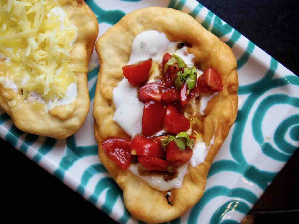 Langos mit Rahm und Tomaten